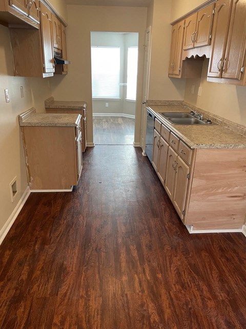 A kitchen with wooden floors and cabinets.