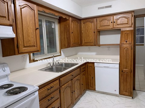 A kitchen with wooden cabinets and a white stove top oven.