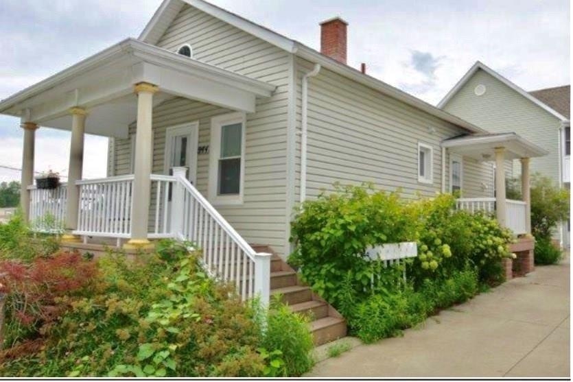 A small house with a porch and a white picket fence.