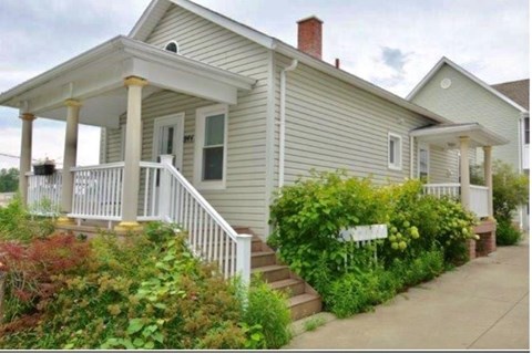 A small house with a porch and a white picket fence.
