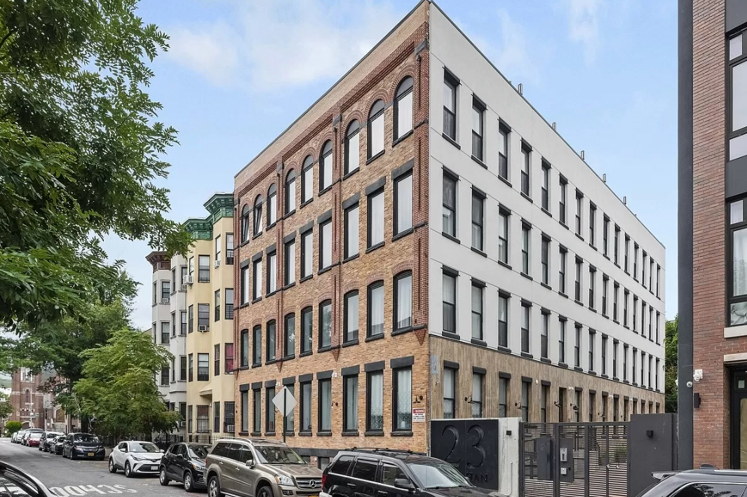 a tall brick building with cars parked in front of it