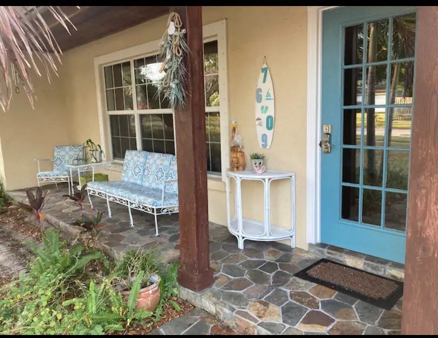 a porch with two chairs and a surfboard on the wall