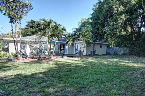 a small white house with palm trees in front of it