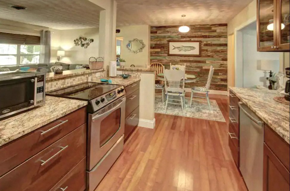 the kitchen and dining area of a home with wood flooring and granite counter tops
