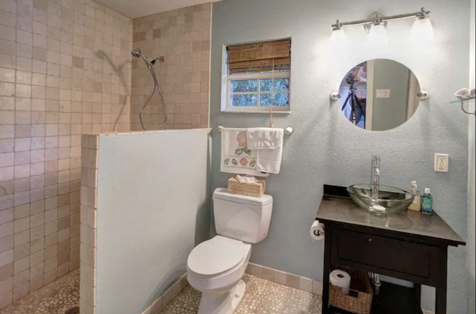 the bathroom has a shower and a toilet and a sink