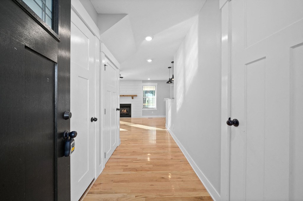 a long hallway with white walls and wooden floors and a black door