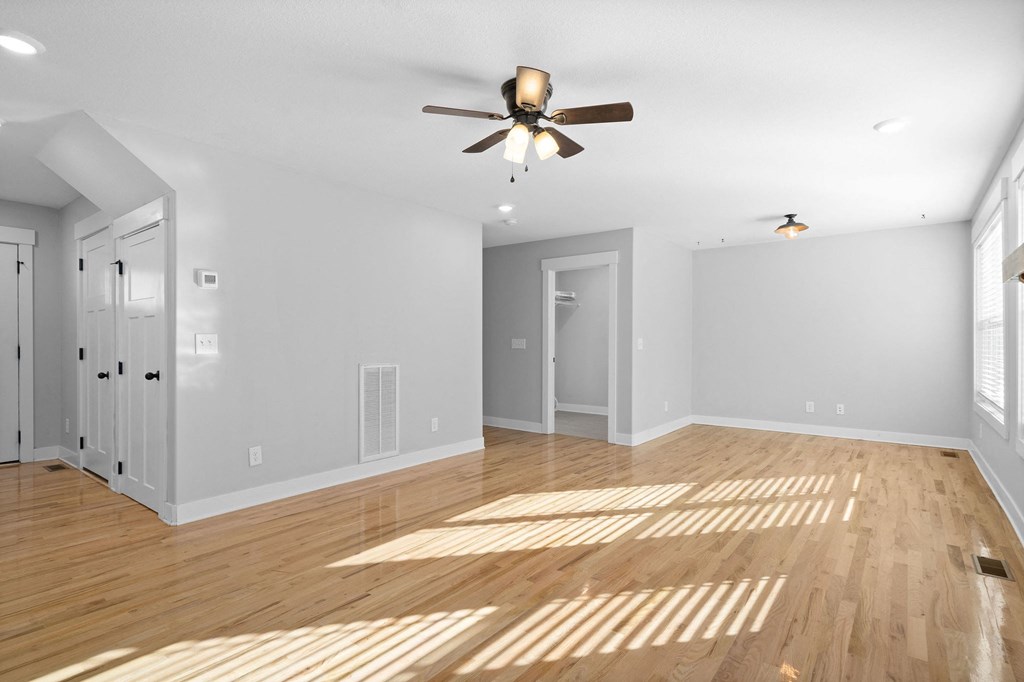 an empty living room with a ceiling fan and hardwood floors