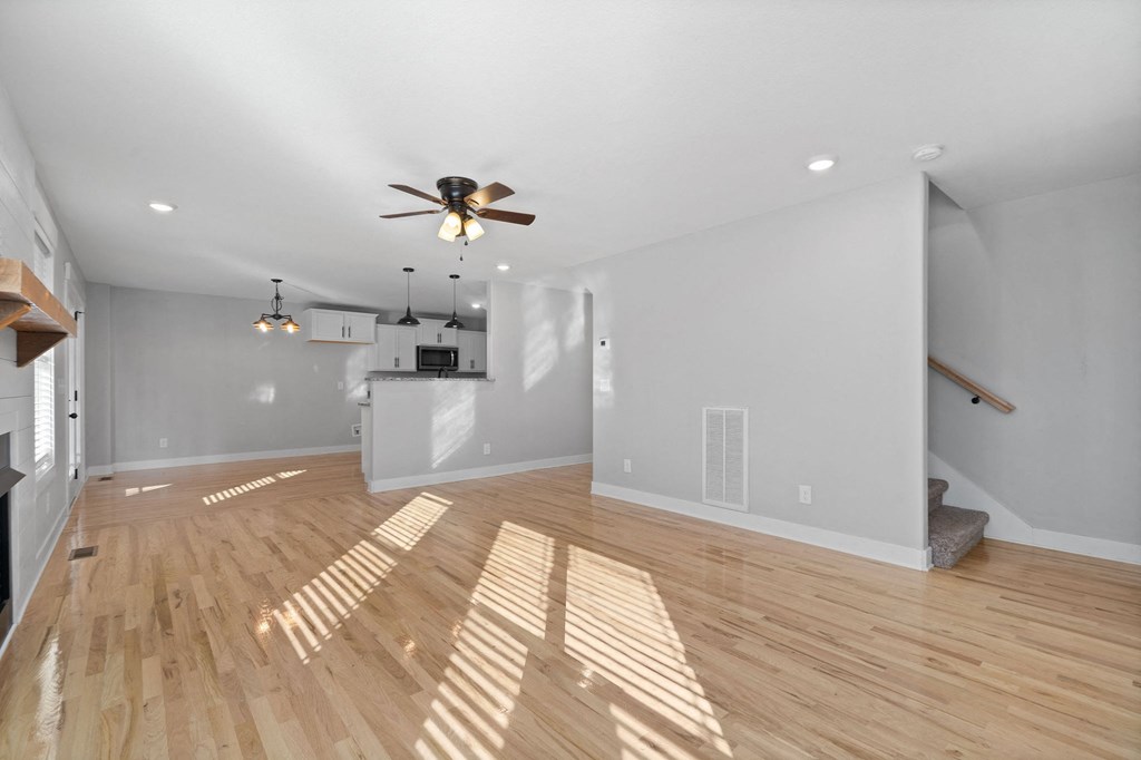 the living room is spacious and has hardwood floors and a ceiling fan