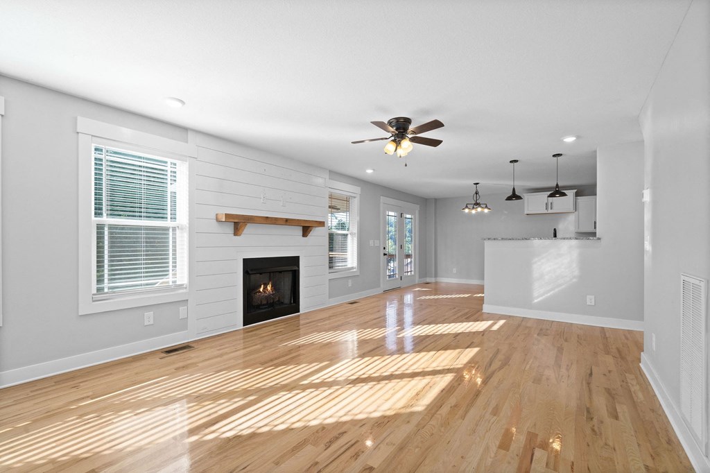 an empty living room with a fireplace and a ceiling fan