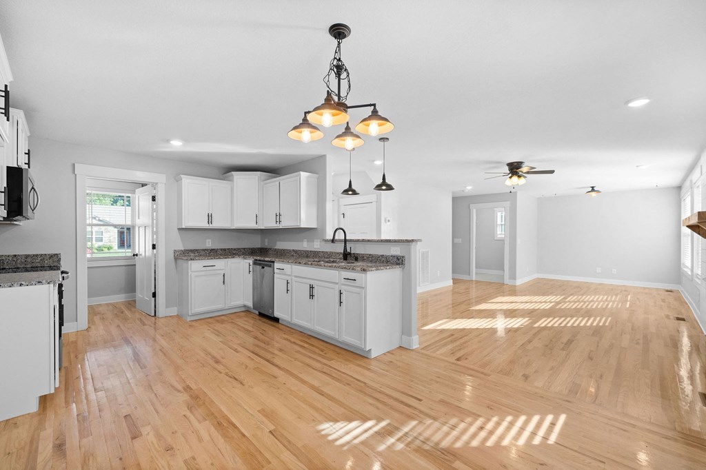 a renovated kitchen with white cabinets and a wood floor