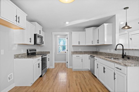 an open kitchen with white cabinets and a counter top