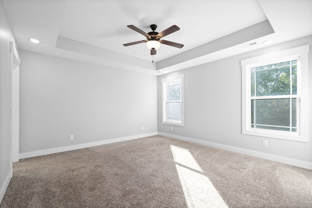 an empty living room with a ceiling fan and a window