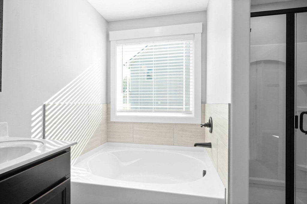 a white bathroom with a tub and a window