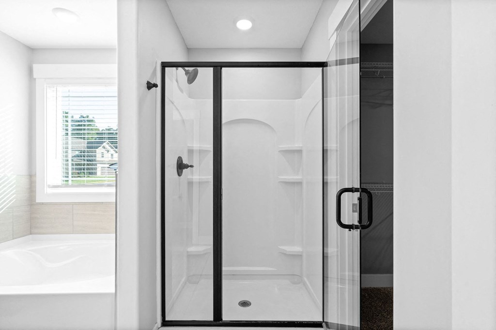 a bathroom with a shower and a tub and a window