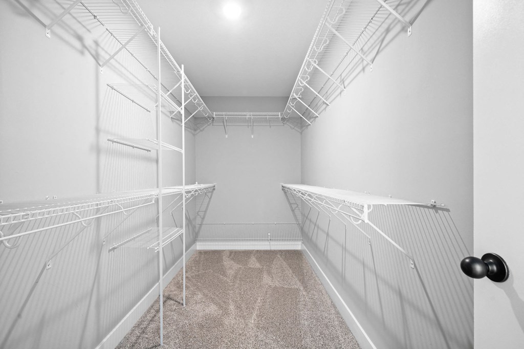 the walk in closet has mirrored closets with white racks