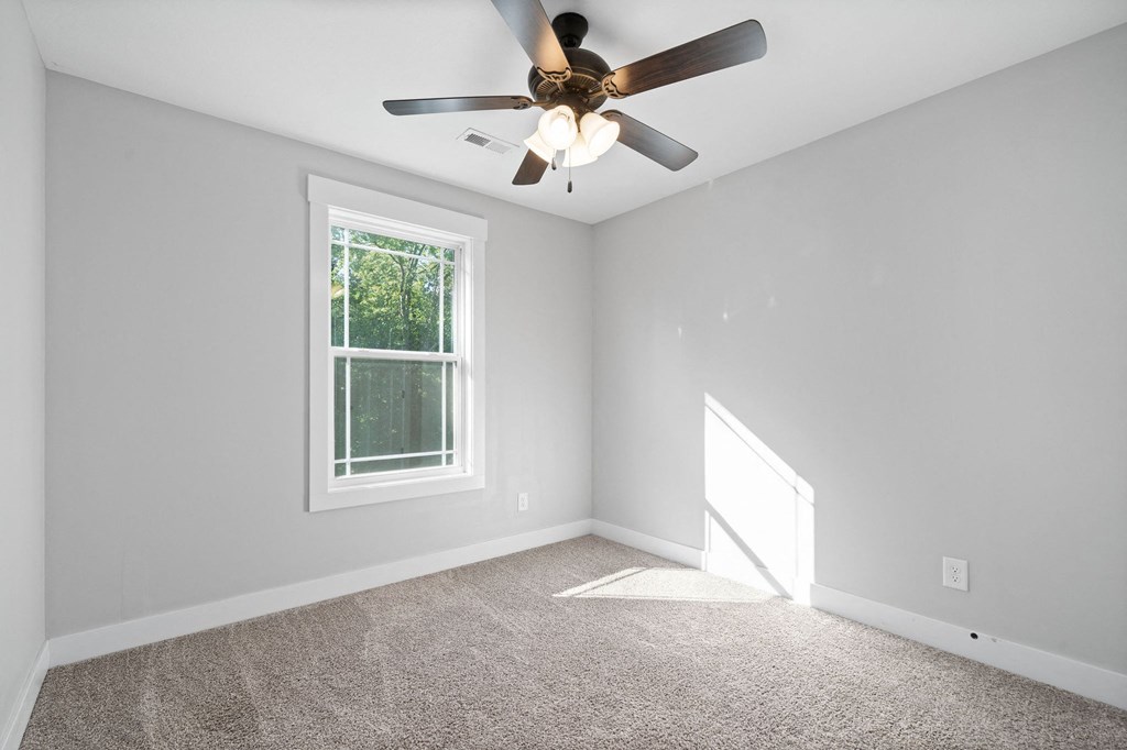 an empty room with a ceiling fan and a window