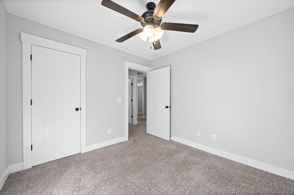 an empty living room with a ceiling fan and white doors
