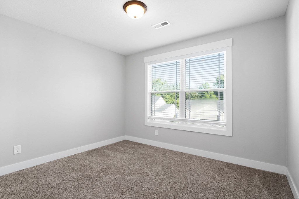 an empty living room with a window and carpet