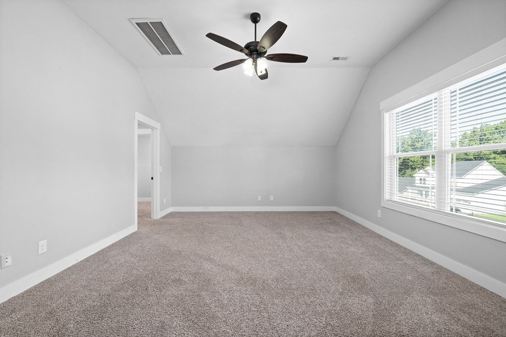 an empty living room with a ceiling fan and a window