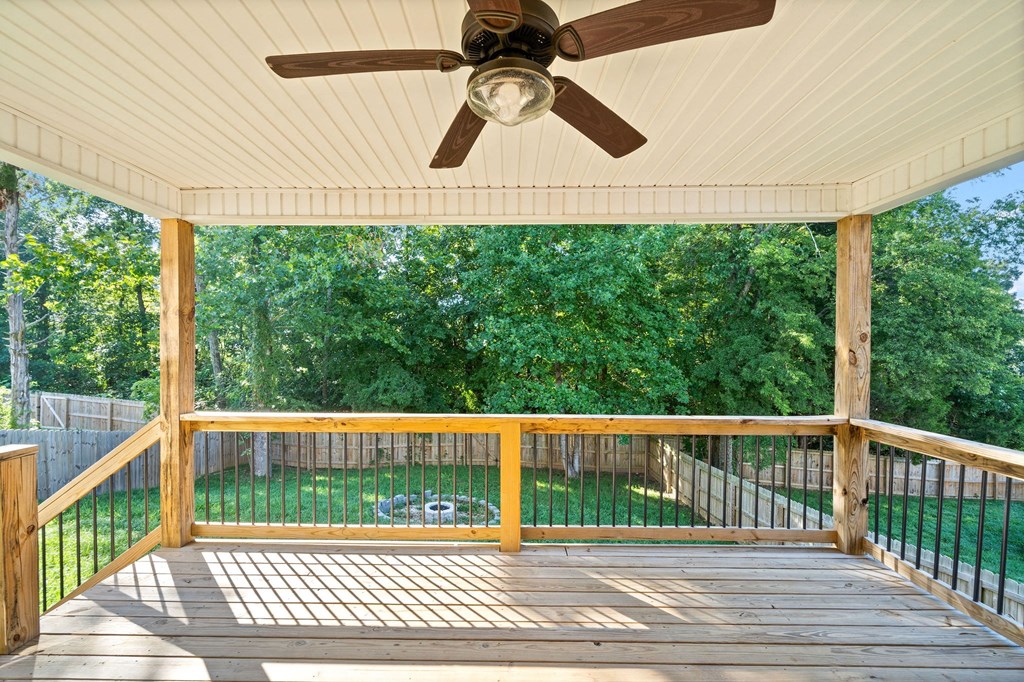 a screened in porch with a ceiling fan and a grass field