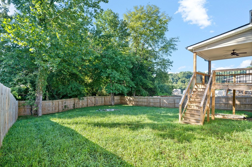 a backyard with a deck and a yard with grass and trees