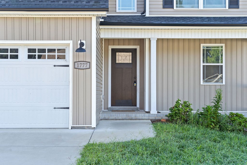 the front door of a house with a driveway and a garage door