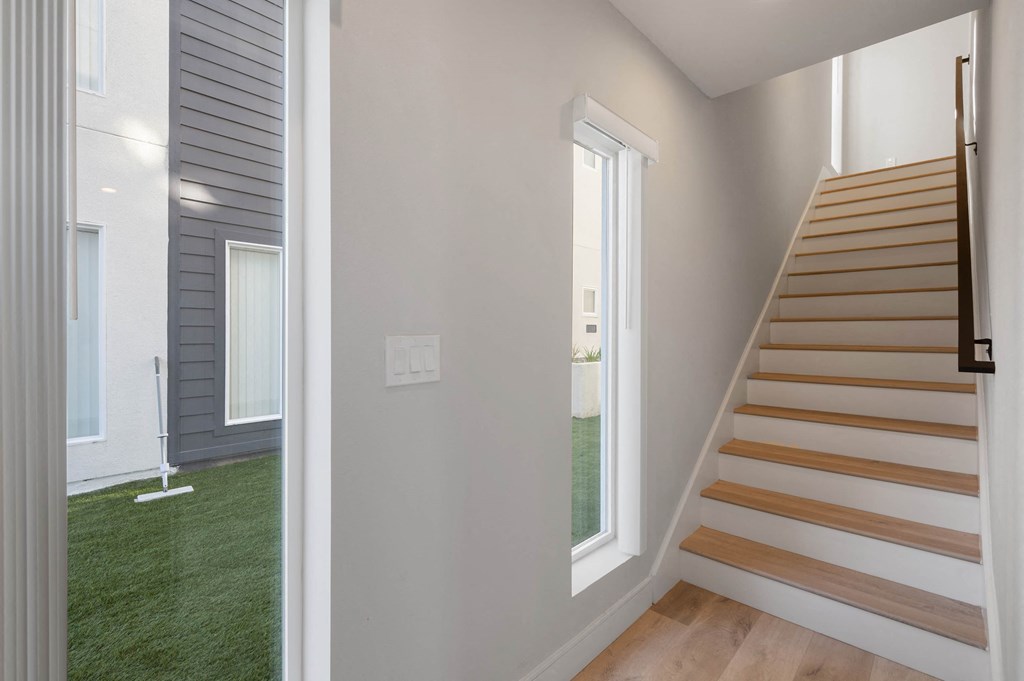 a renovated house with white walls and a staircase with a window and a green carpet