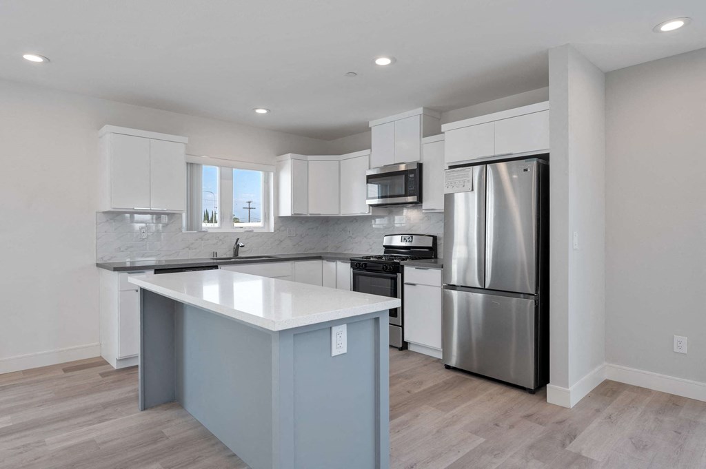 a renovated kitchen with white cabinets and stainless steel appliances