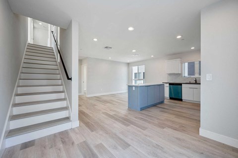 a renovated living room with a staircase and a kitchen with a blue cabinet