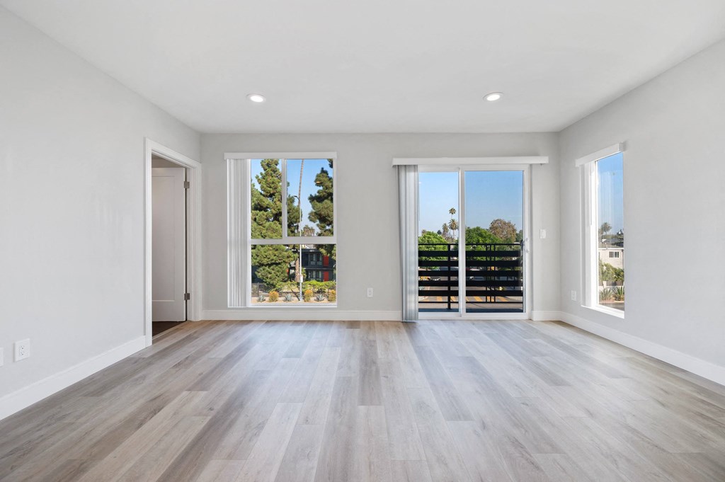 a living room with white walls and wood floors and sliding glass doors