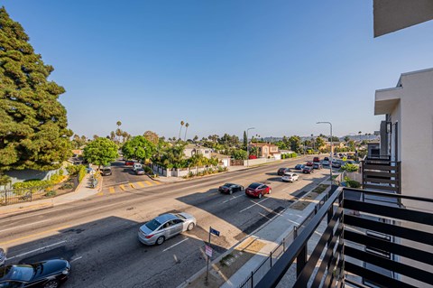 a view of the street from a balcony with cars on the road