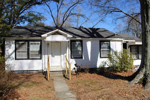 a white house with a porch and a sidewalk in front of it
