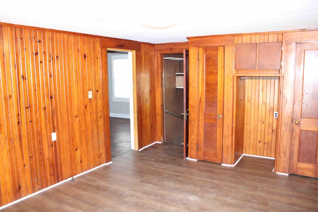 an empty living room with wood paneled walls and a wood floor
