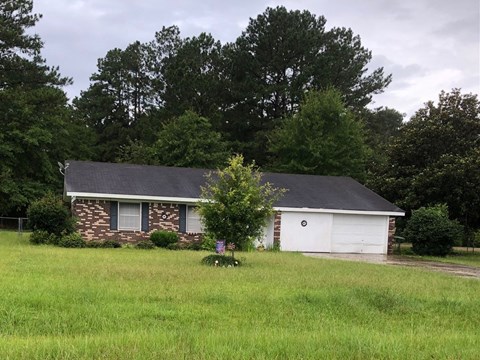 a small brick house with a tree in front of it in a field