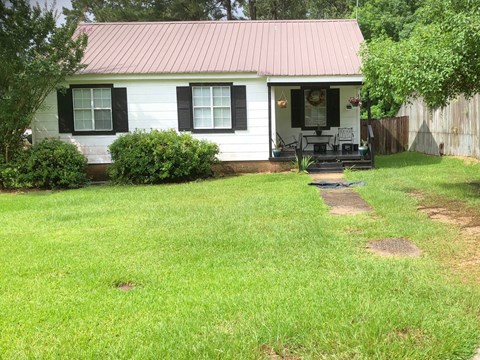 a small white house with a yard and a porch