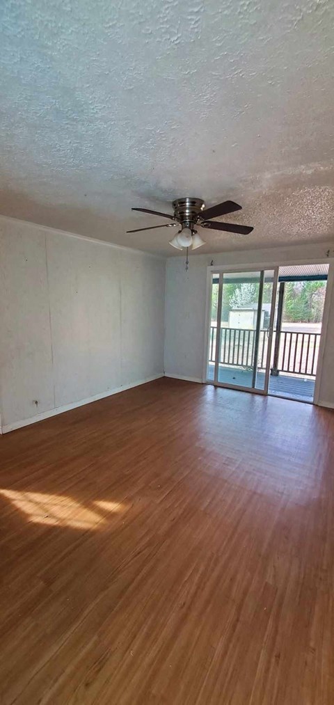 an empty living room with wood floors and a ceiling fan