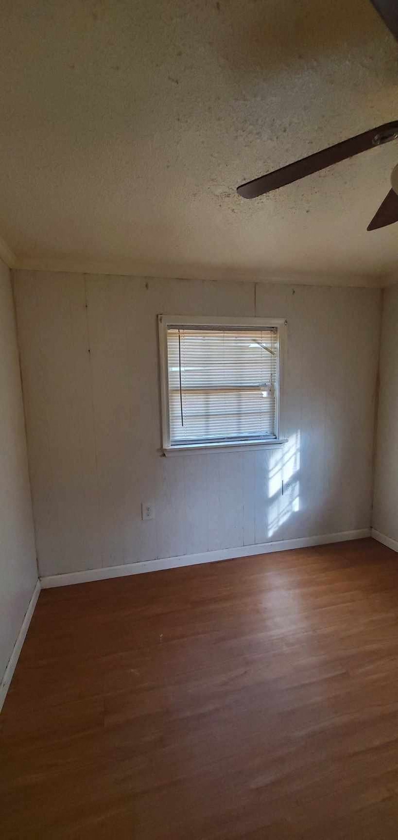 an empty room with a window and wooden floors