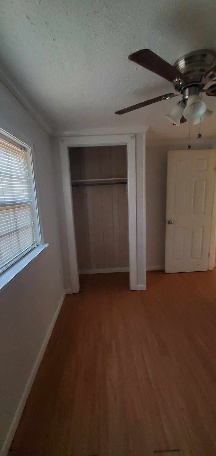 an empty room with a ceiling fan and a closet