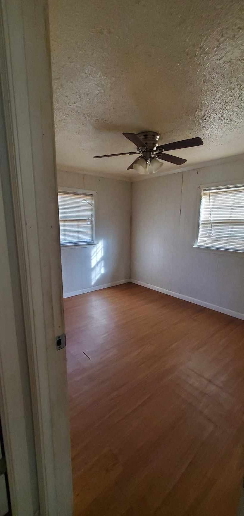 an empty room with a ceiling fan and wood floors