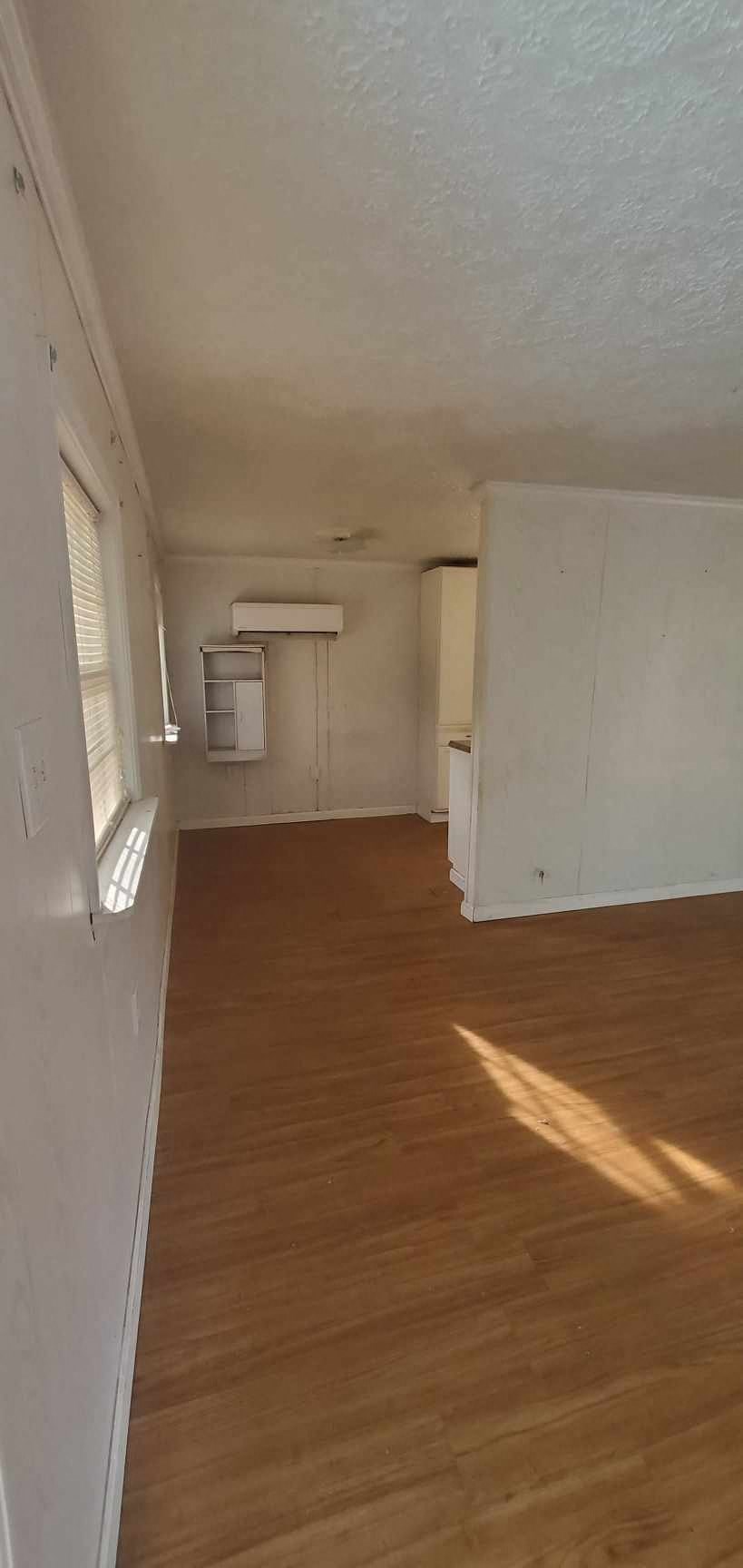 an empty living room with a wood floor and white walls