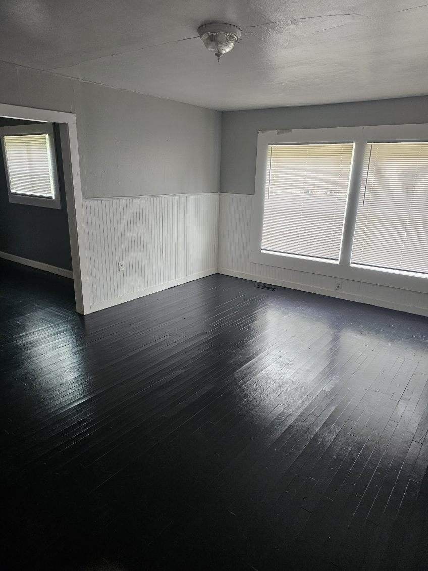 an empty living room with wood floors and windows