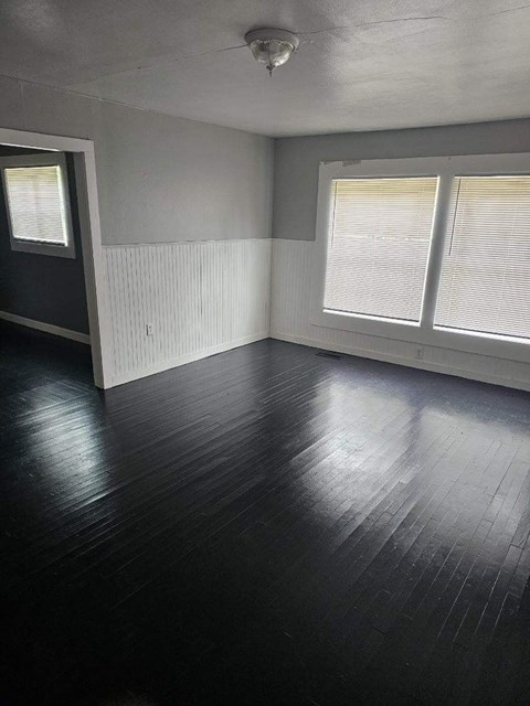 an empty living room with wood floors and windows