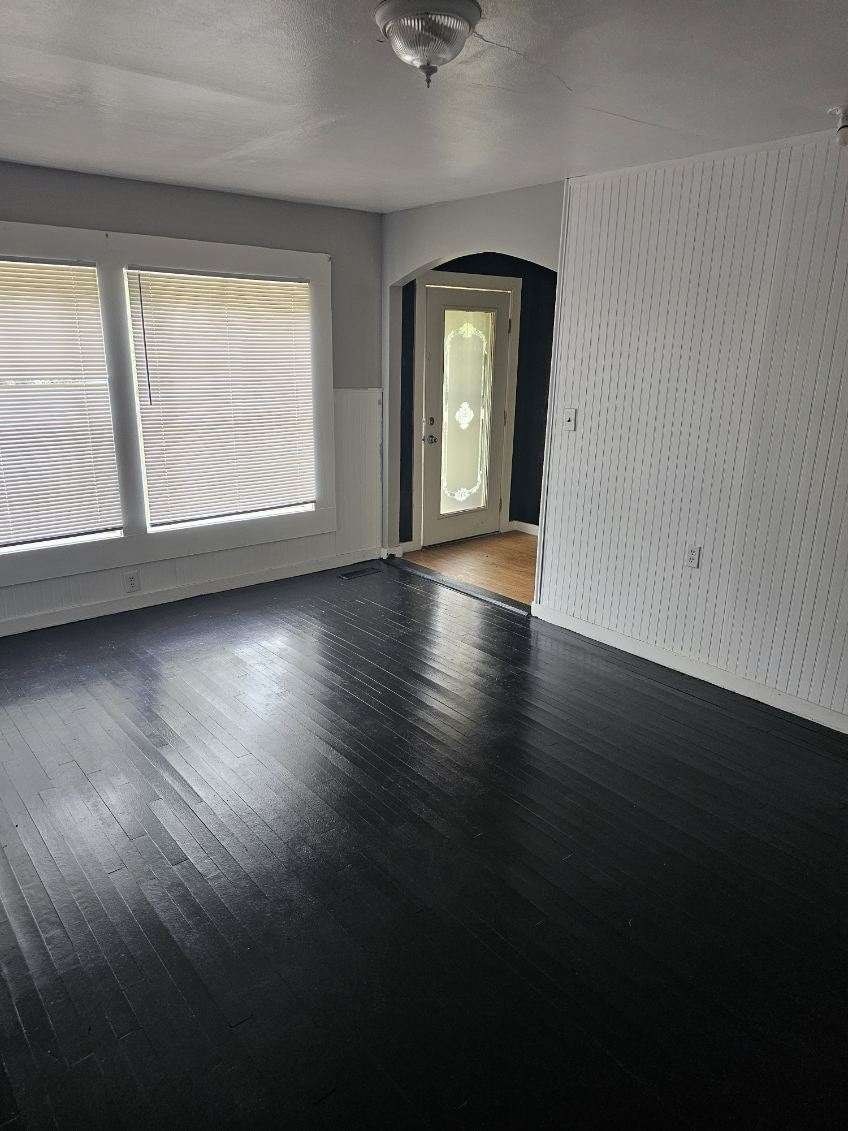 an empty living room with wood flooring and large windows