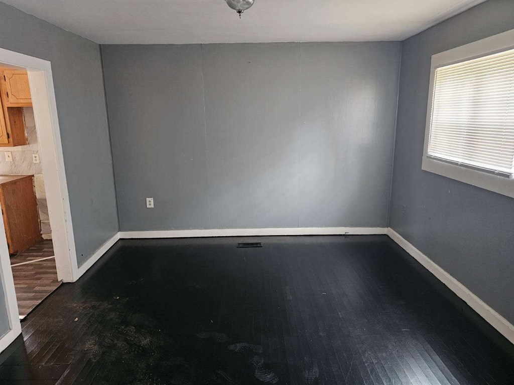 an empty room with a hard wood floor and gray walls