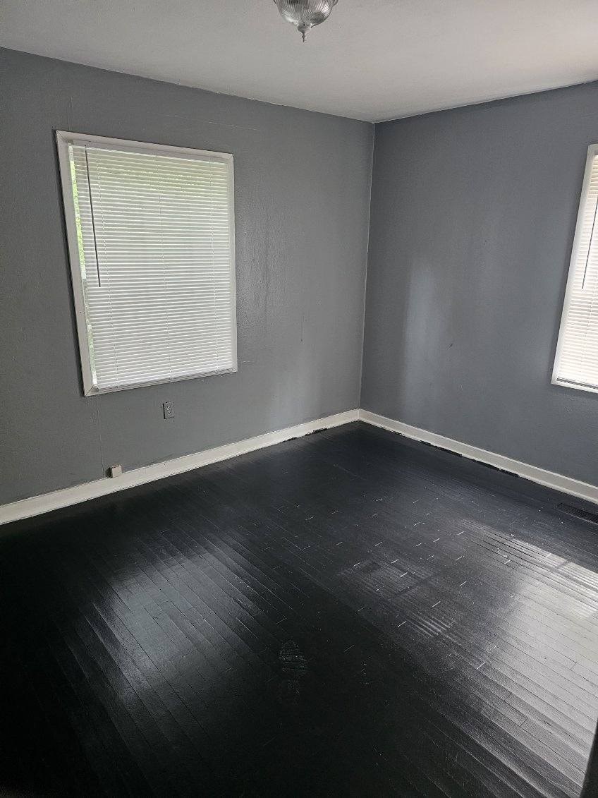 an empty room with black wood floors and a window