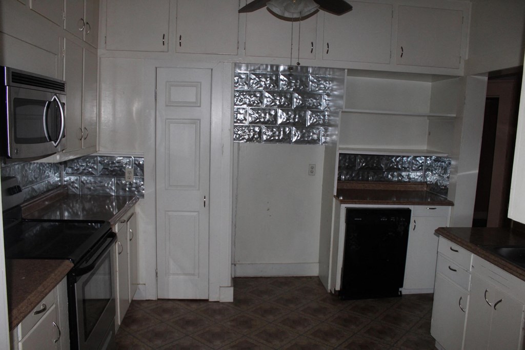 A kitchen with white cabinets and a black stove top oven.