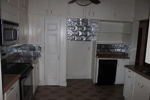 A kitchen with white cabinets and a black stove top oven.