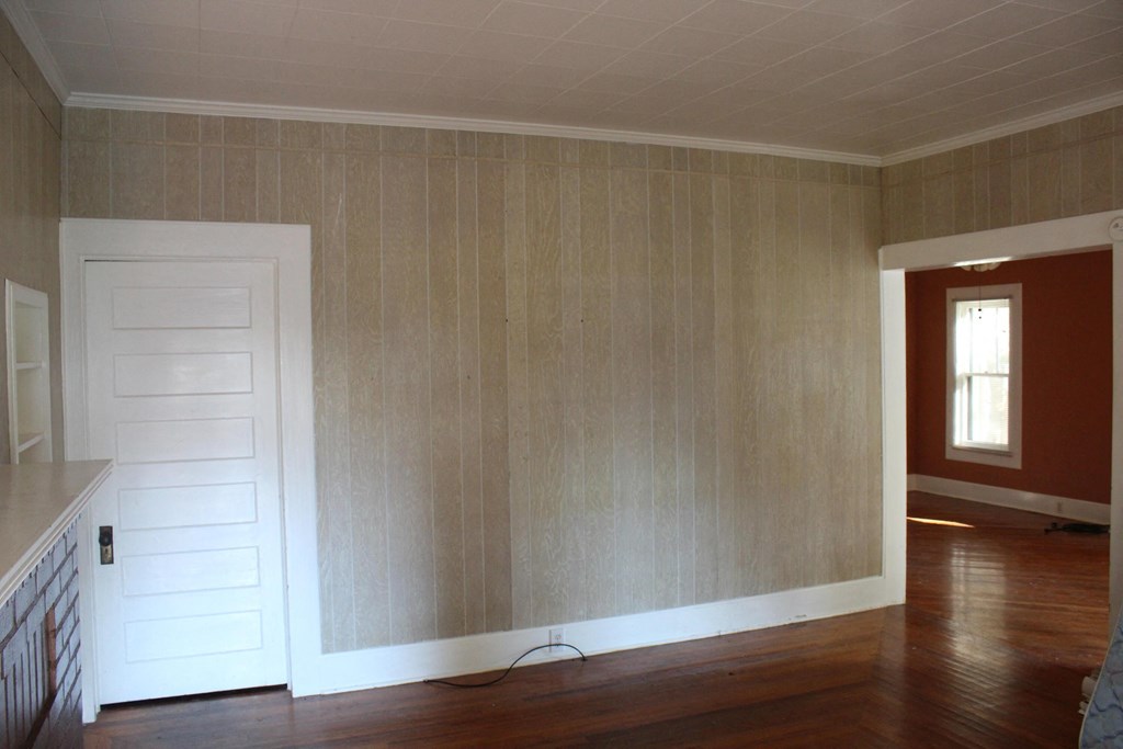 A room with a white door and wooden walls.