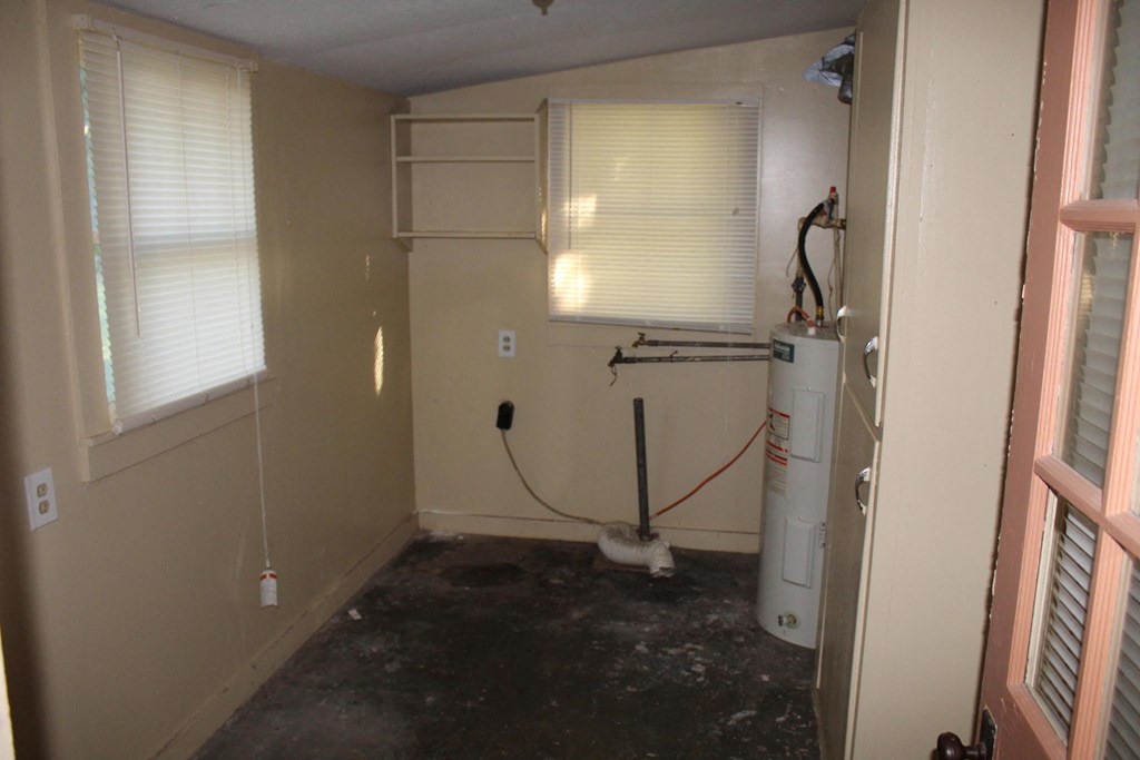 A room with a white wall and a window with blinds.