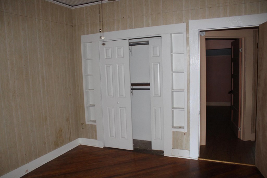 A room with a white door and a brown floor.